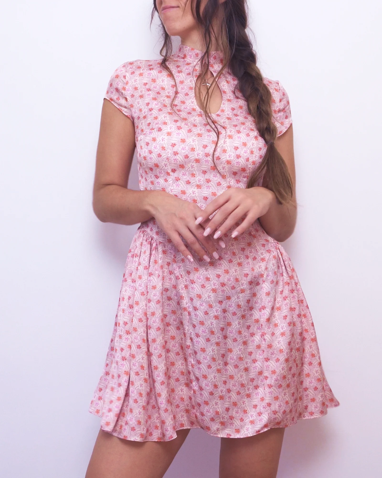 Angled front view of the pink floral Ayris mini dress with a fitted waist and full gathered side skirt panels.