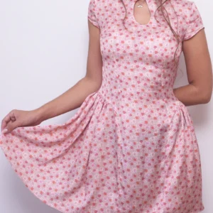 Model holding out the pink floral Ayris mini dress skirt to show its gathered side panels and volume.
