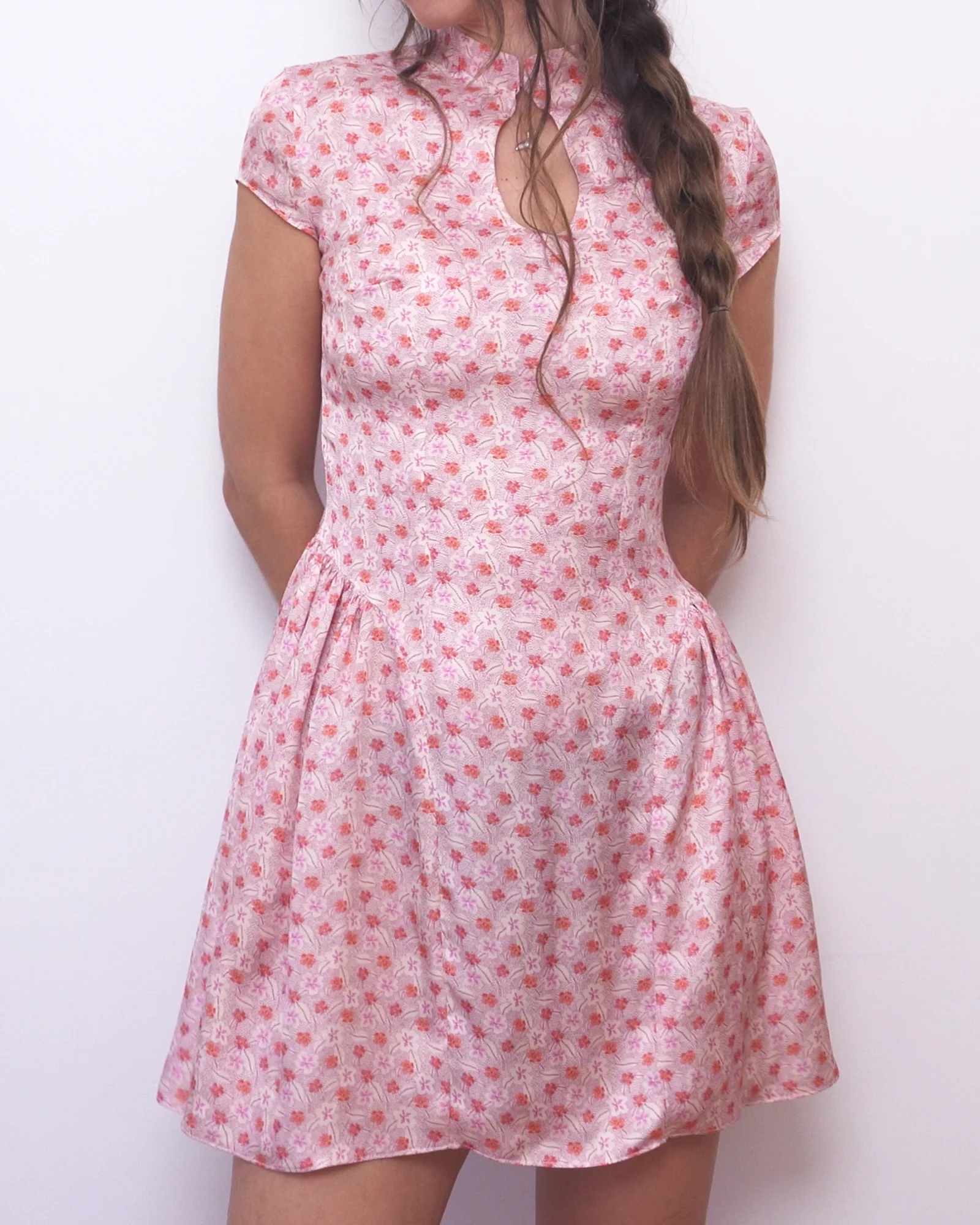 Angled view of the pink floral Ayris mini dress with gathered side panels and a fitted waist.